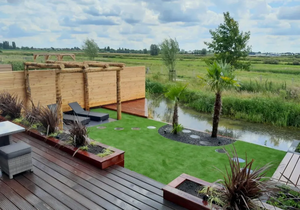 Exotische tuin aan het water met vlonder en pergola, aangelegd door Maxx Tuinen
