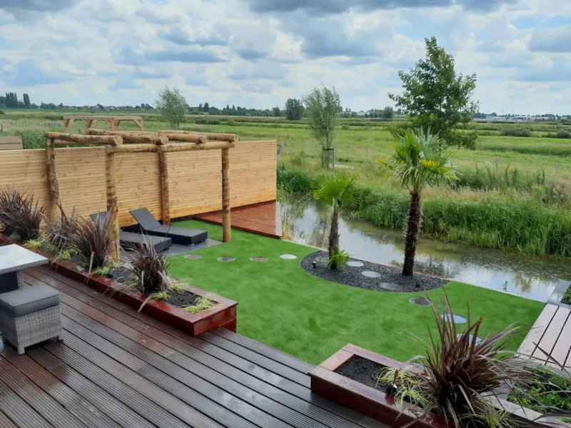 Exotische tuin aan het water met vlonder, pergola en palmen